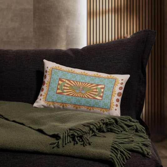 Decorative pillow with a butterfly design on a dark sofa with a green throw blanket.