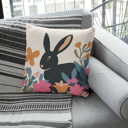 The Baxter bunny decorative throw pillow on a couch with a throw blanket.