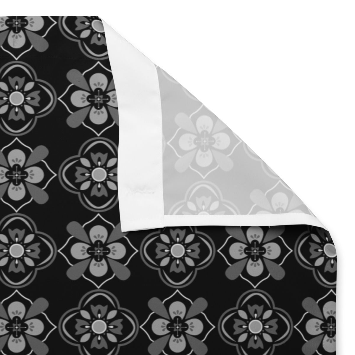 Floral patterned fabric shower curtain with black, gray, and white colors and sewn holes for shower rings.