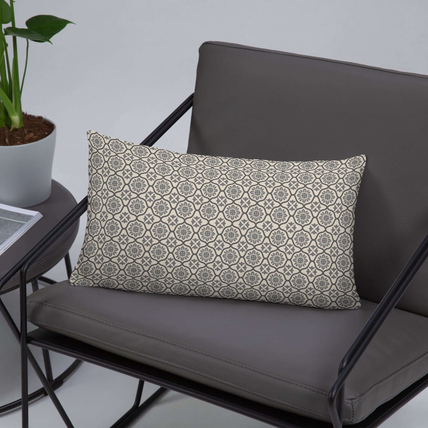 Lifestyle mockup of the Nina lumbar satin polyester throw pillow in a modern gray leather chair.
