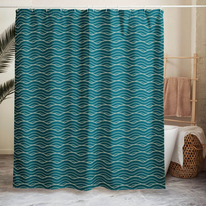 The Oliver shower curtain hangs in front of a tub with a wood wicker basket and wooden towel bar, doubling as a room divider.