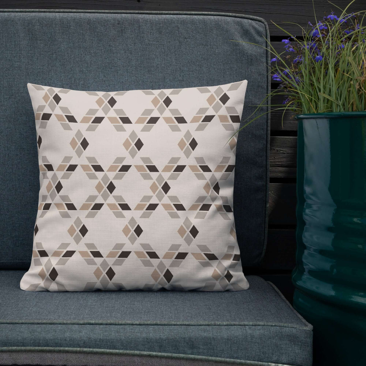 The Saige decorative throw pillow on an outdoor patio couch surrounded by potted flowers