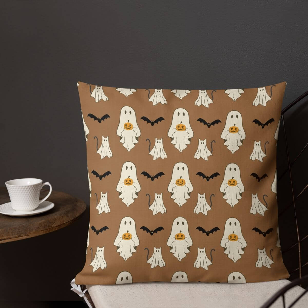 Halloween-themed pillow with ghosts, cats, and bats on a brown background