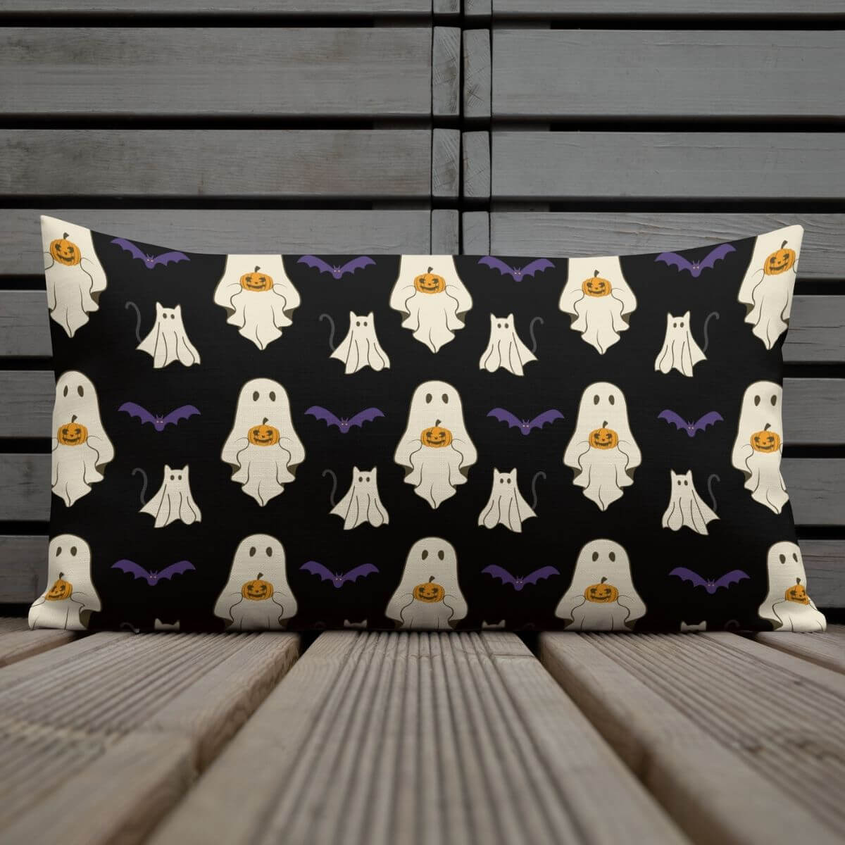 Halloween-themed pillow with ghost and pumpkin pattern on a wooden surface