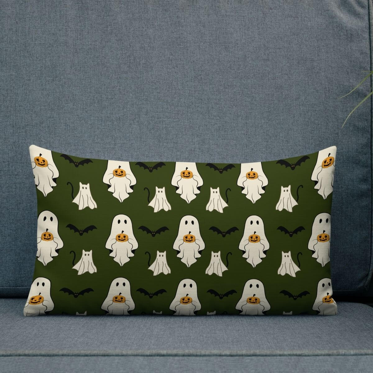 Decorative pillow with Halloween-themed pattern featuring ghosts, pumpkins, and bats on a green background.