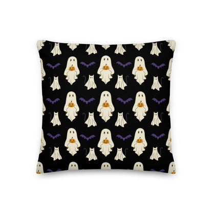 Halloween pillow with ghosts, cats, bats, and pumpkins against a black background.
