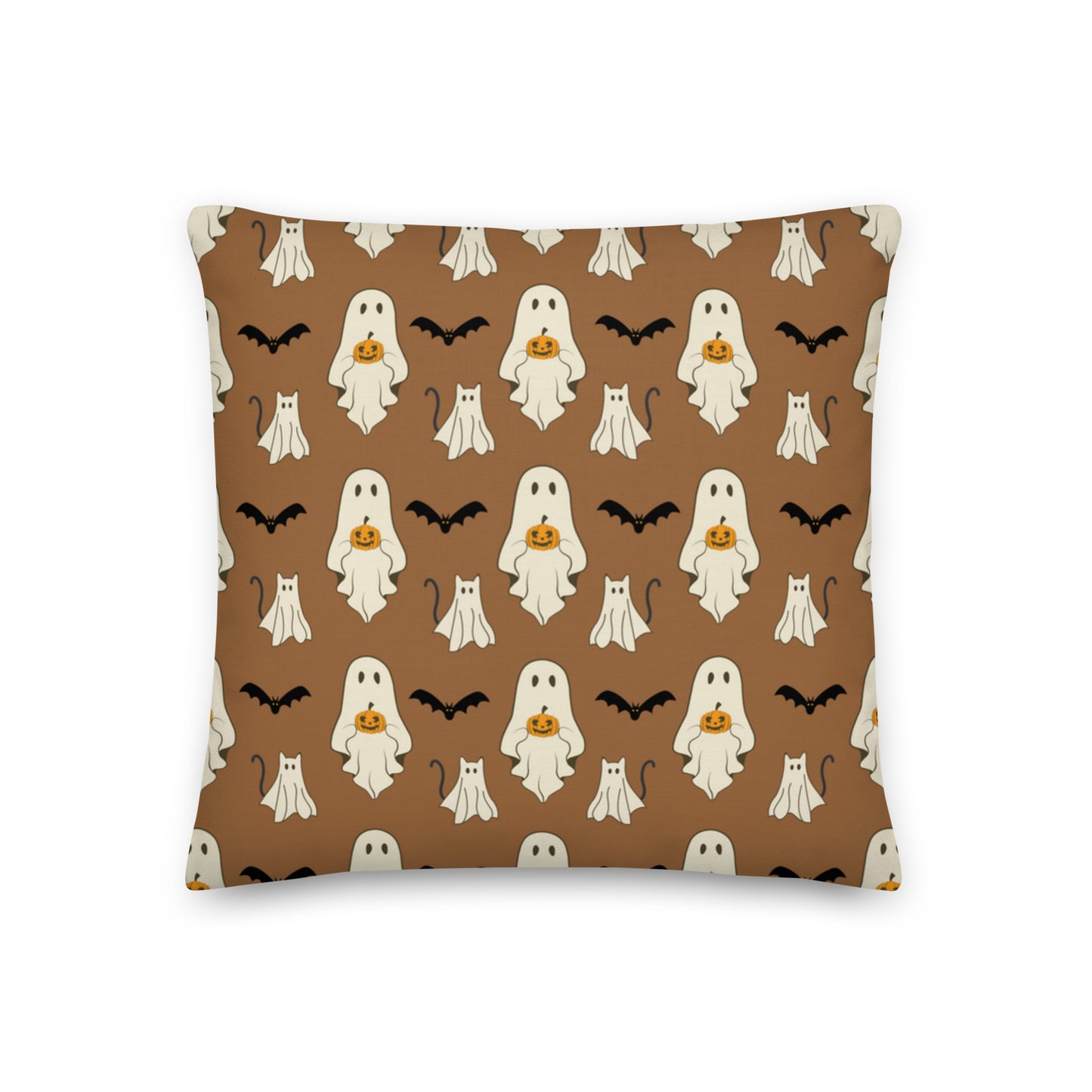 Halloween pillow with ghosts, cats, bats, and pumpkins against a brown background.