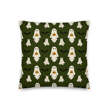 Halloween pillow with ghosts, cats, bats, and pumpkins against a green background.