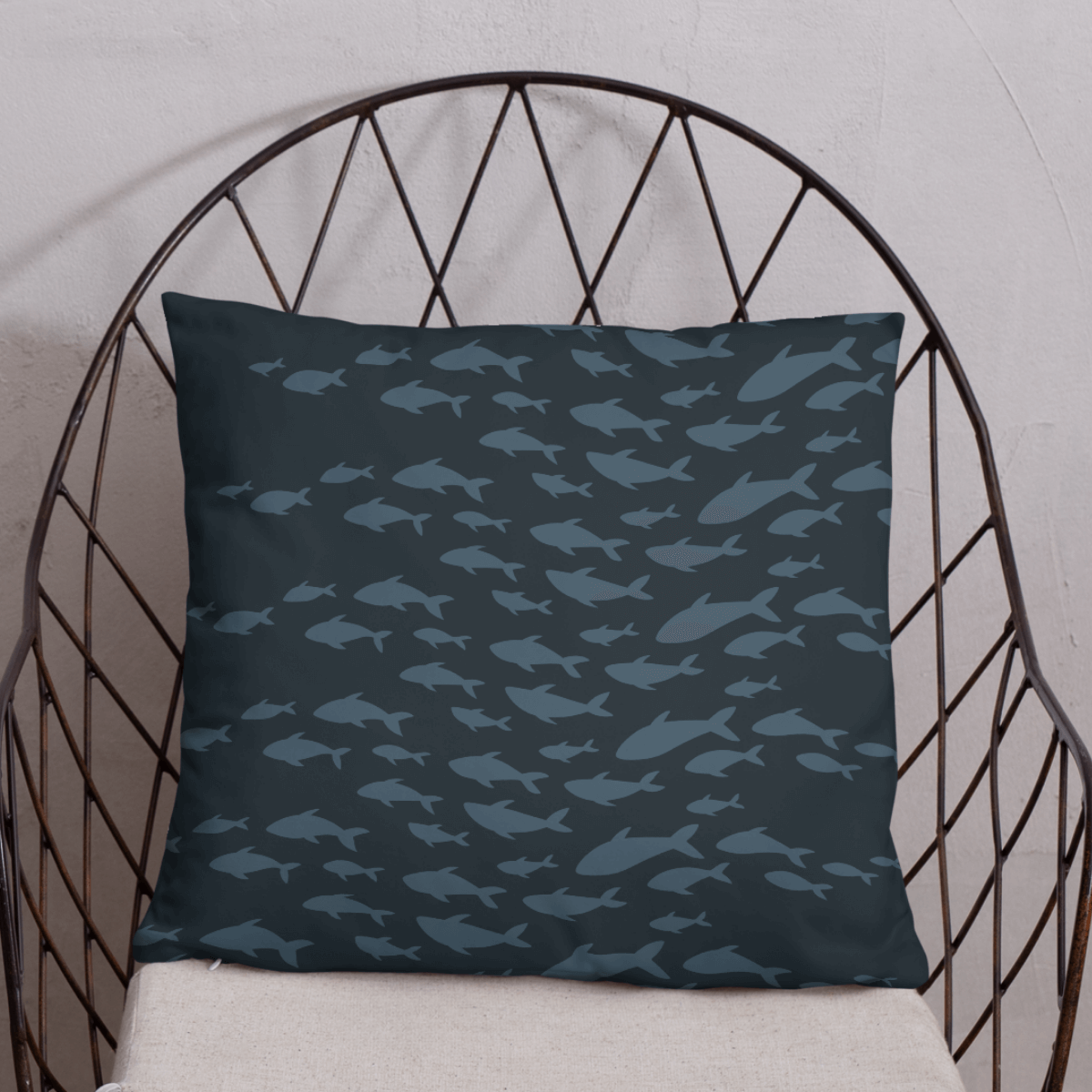 Decorative pillow with a whimsical fish pattern on a wire chair against a white wall