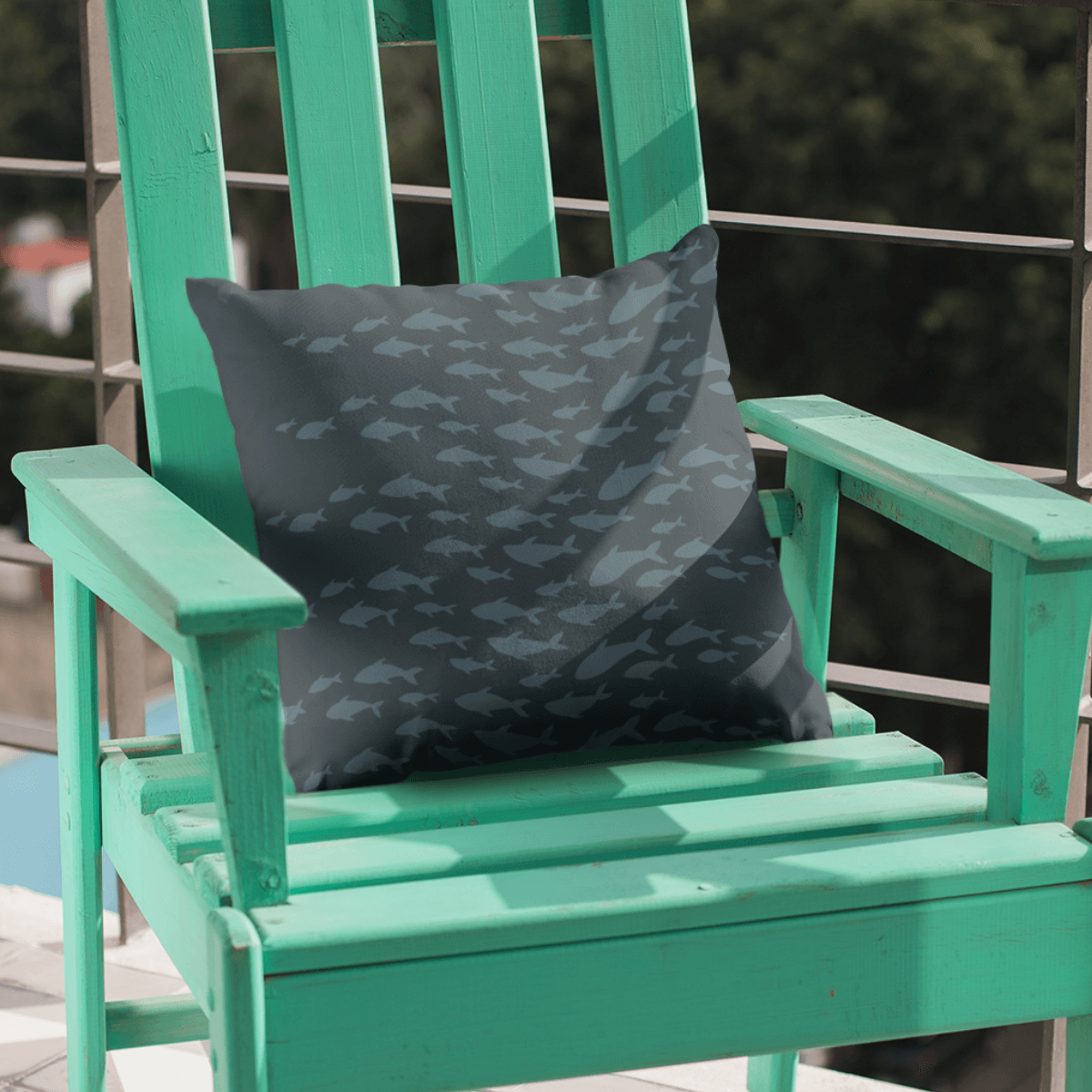 Navy blue pillow featuring a fish pattern in an Adirondack chair for a seaside retreat vibe.