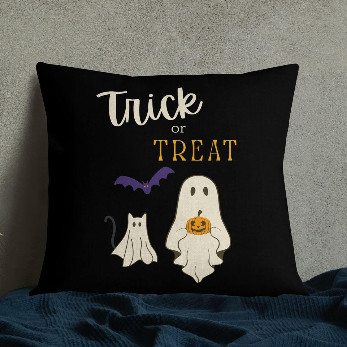 Black pillow with Halloween-themed design featuring a ghost, cat, and bat on a dark background.