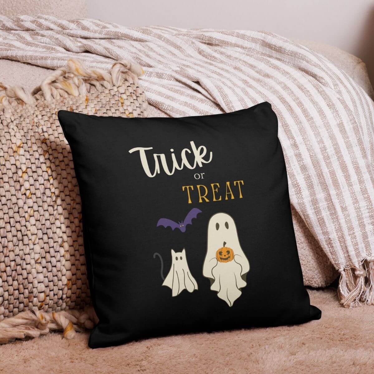 Black pillow with Halloween-themed design featuring ghosts, a bat, and 'Trick or Treat' text on a textured surface.