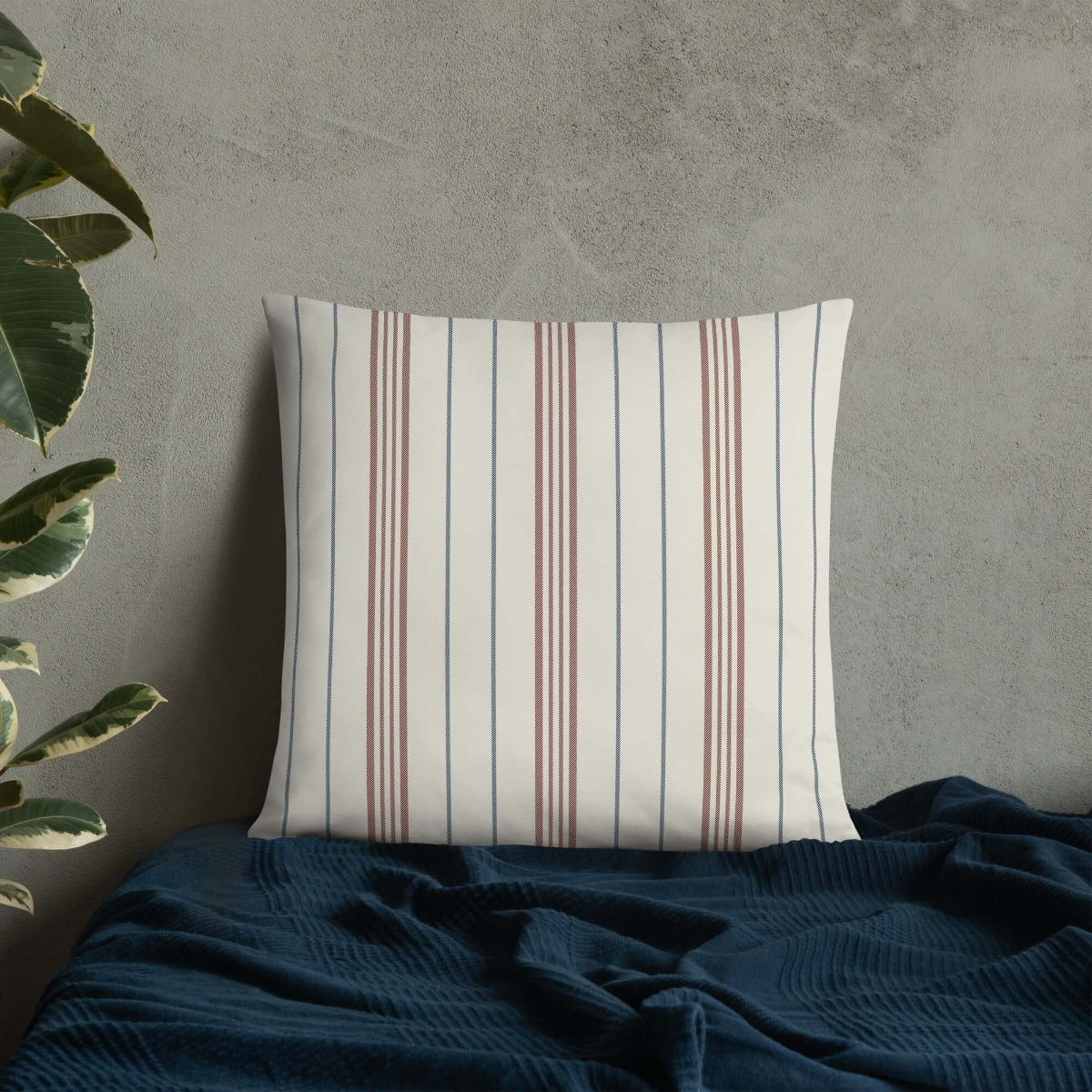 The meadow striped accent pillow on a blue blanket