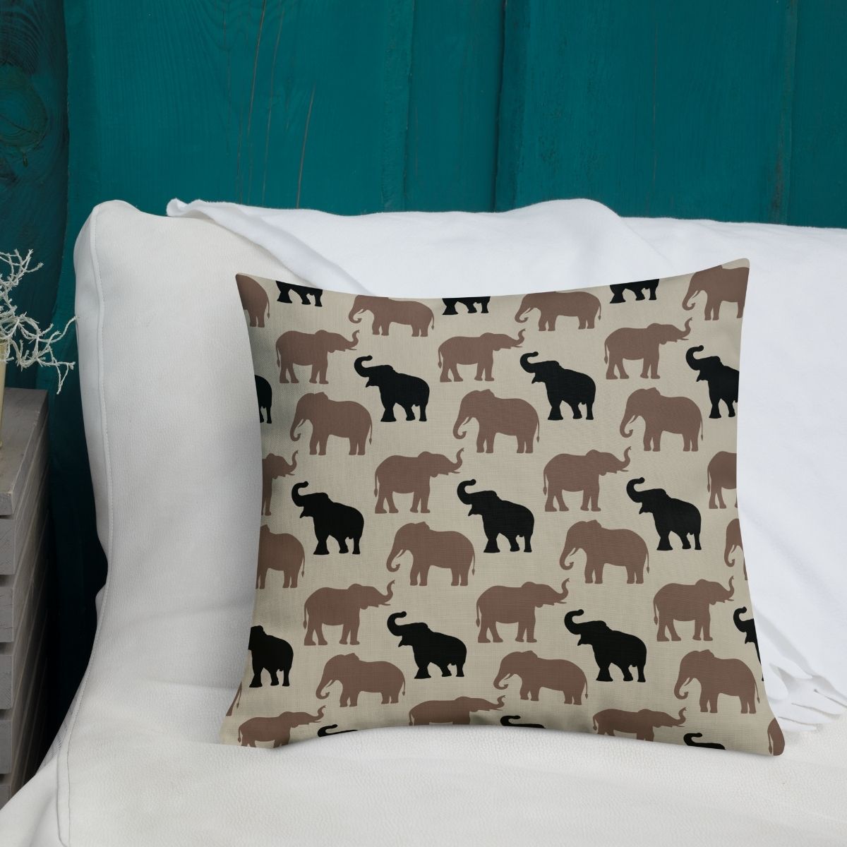 Olivia is a decorative pillow featuring an elephant pattern, set against a white couch on a teal wall, creating a modern, earthy vibe.