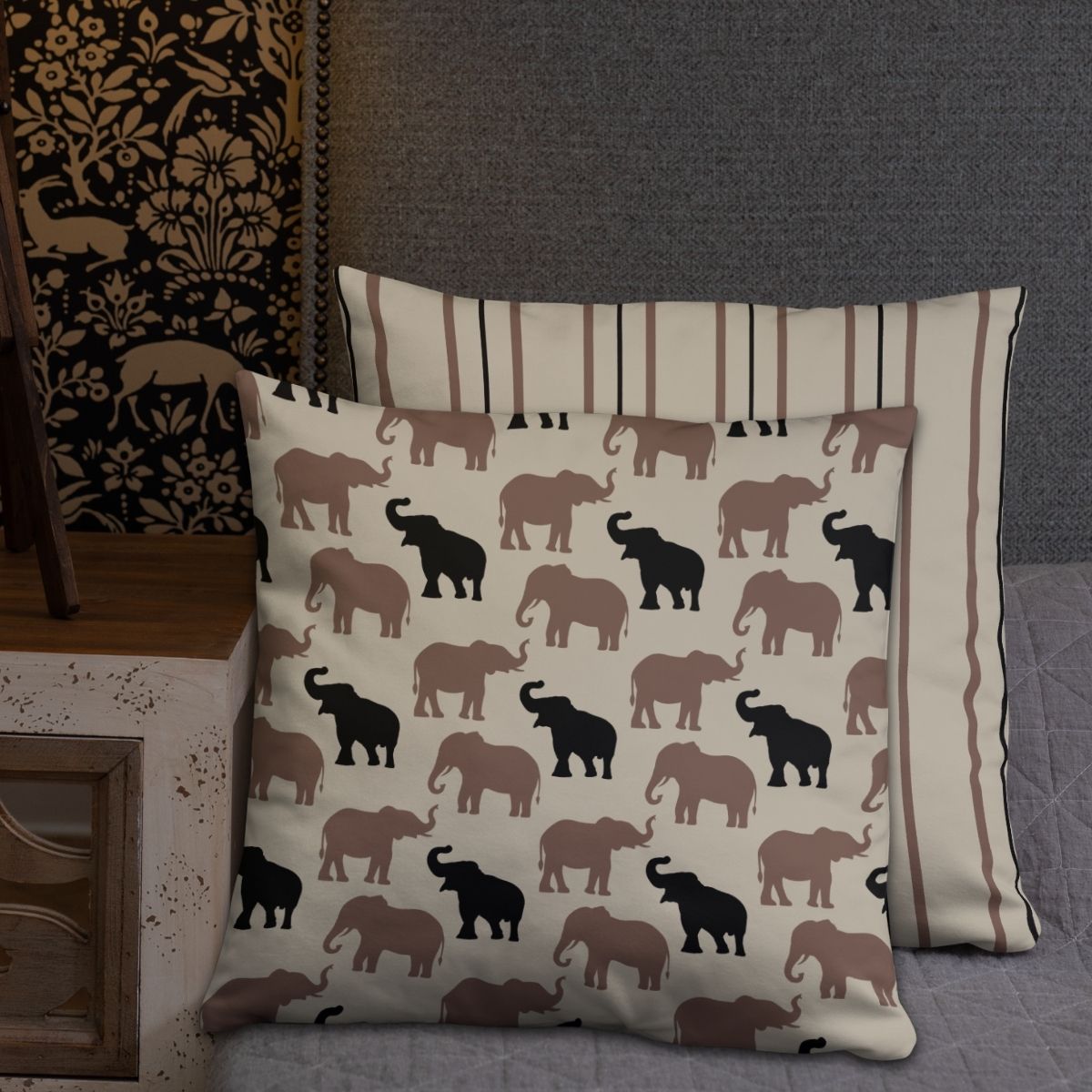 Two Olivia accent pillows are shown on a bed showcasing the elephant pattern on the front pillow and the striped reverse side on the back pillow.
