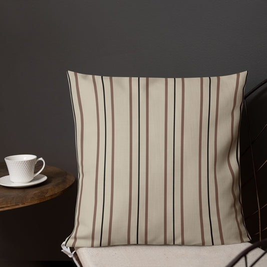 A striped pillow on a chair with an elephant pattern on the reverse side is shown, accompanied by a cup of coffee on a small table against a dark wall.