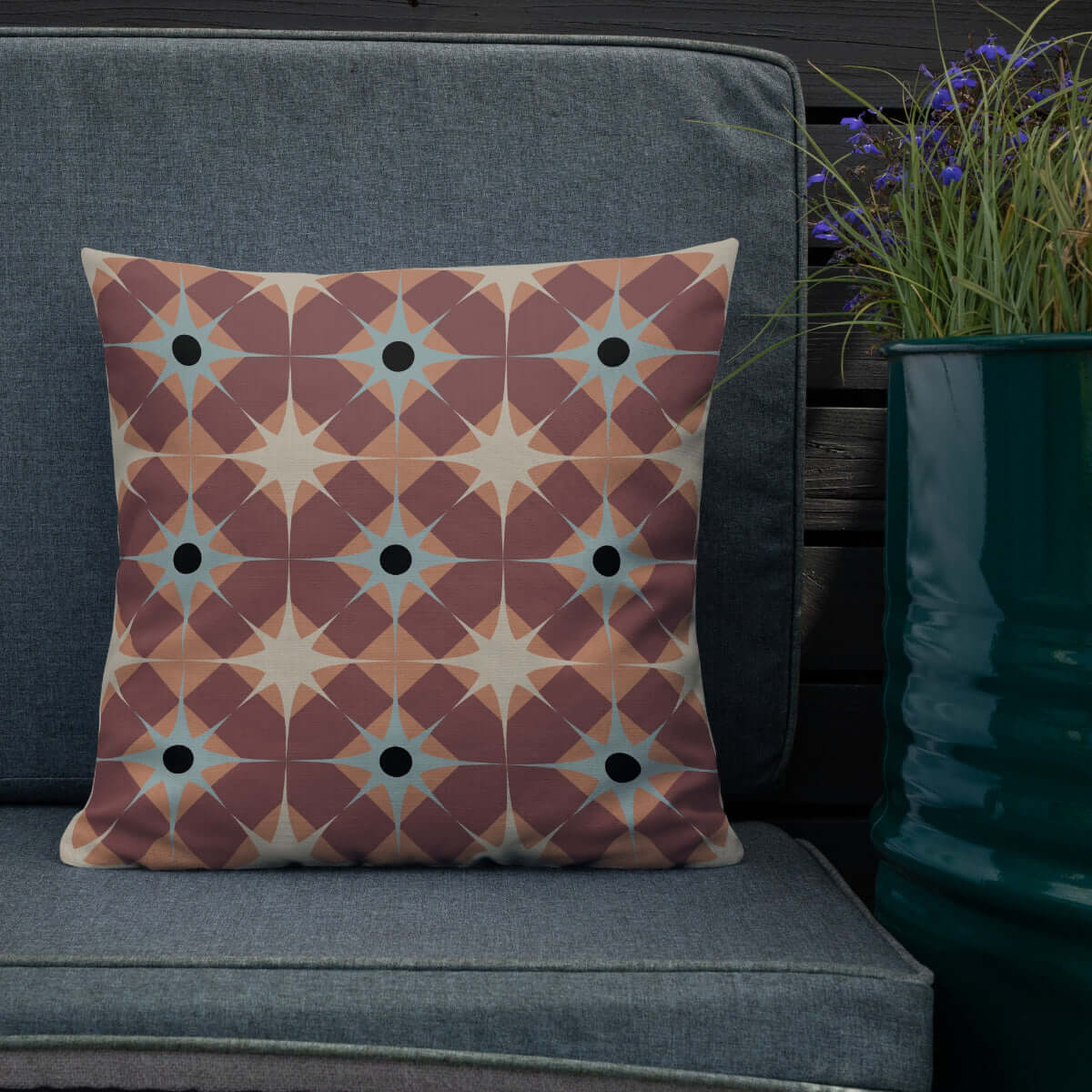 The Pepper pillow on a patio chair next to flowers.