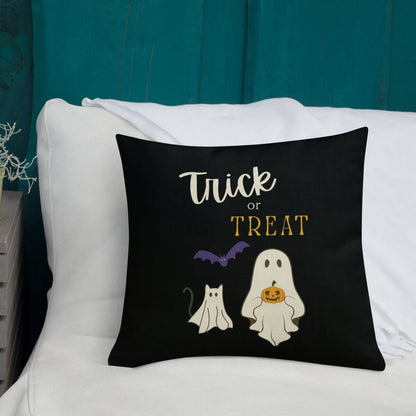 Halloween-themed pillow with 'Trick or Treat' text and ghost illustrations on a white couch.