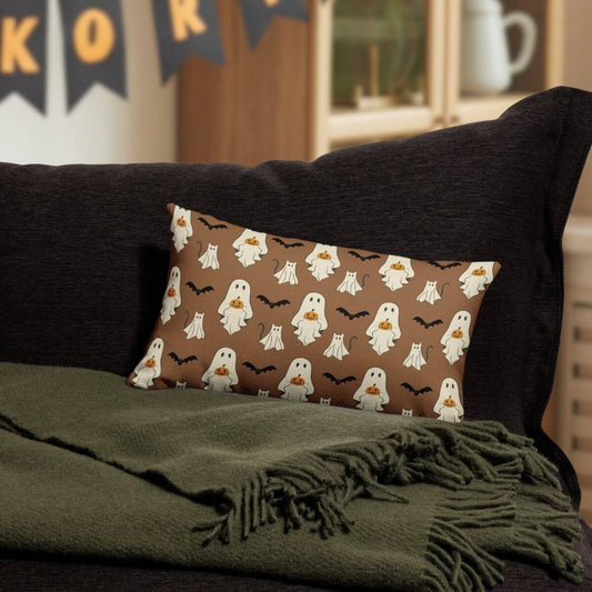 Halloween-themed pillow with ghost pattern on a dark couch with green blanket
